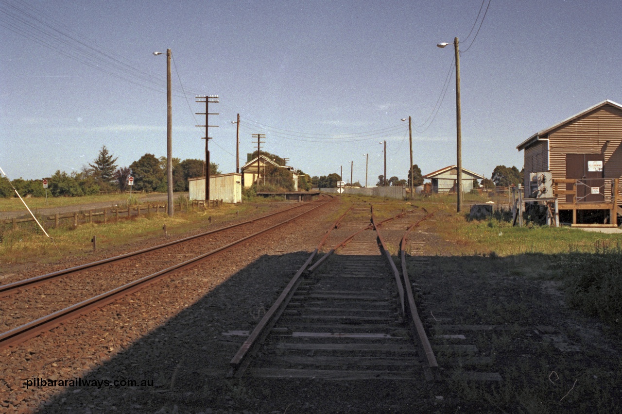 129-1-37
Koo Wee Rup station overview, shows removed track, looking in the up direction towards Melbourne, goods shed fenced off, gangers trolley shed at left in front of station building and platform. [url=https://goo.gl/maps/MChmwk7sx8yYrrxR7]Location is here[/url].
