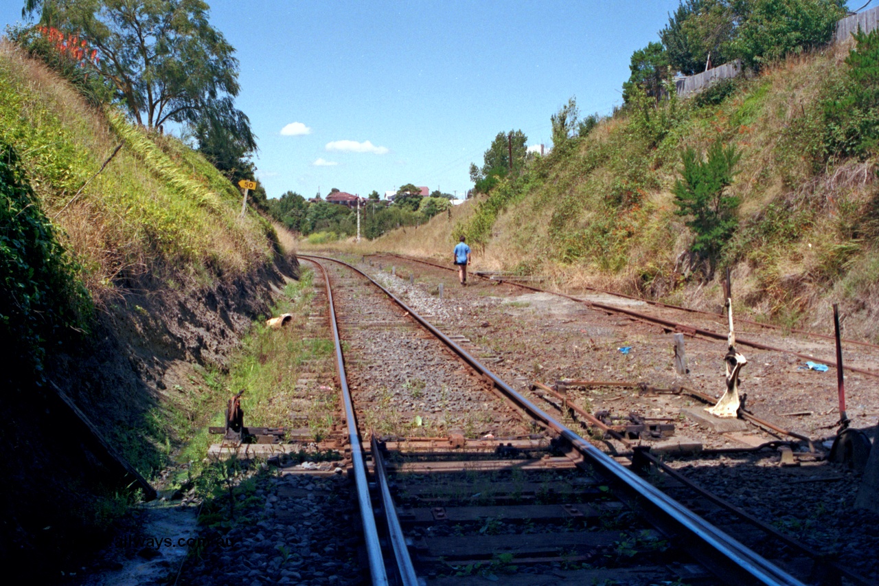 129-2-17
Korumburra track view, looking in the down direction from underneath Bridge Street, former Outtrim - Coal Creek line with baulks on right, Port Albert - Yarram line curving around to the left, points, points and signal lever with interlocking and rodding.

