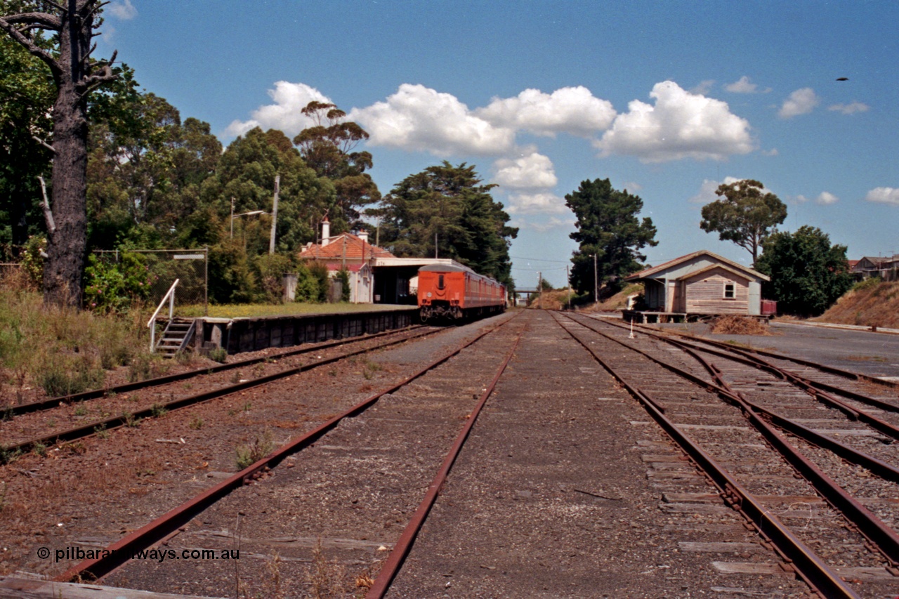 129-2-31
Leongatha station overview, looking east, stabled passenger train H set at platform, goods shed on right.
