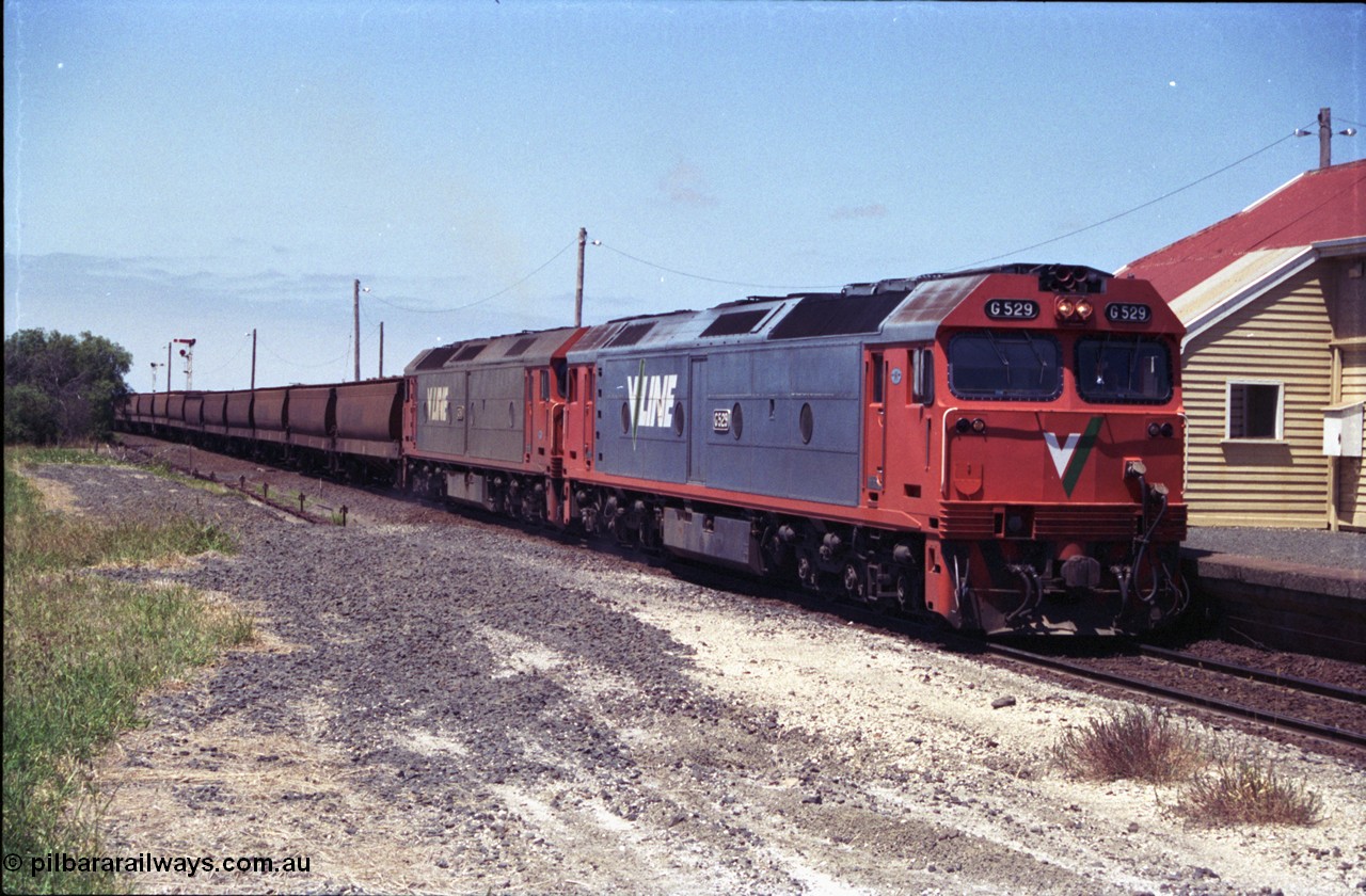 133-18
Gheringhap station building, V/Line broad gauge grain train 9121 heading to Ballarat and beyond, G class G 529 Clyde Engineering EMD model JT26C-2SS serial 88-1259 and G 511 serial 84-1239 pause to exchange electric staves, safeworking, from former No.2 platform.
Keywords: G-class;G529;Clyde-Engineering-Somerton-Victoria;EMD;JT26C-2SS;88-1259;