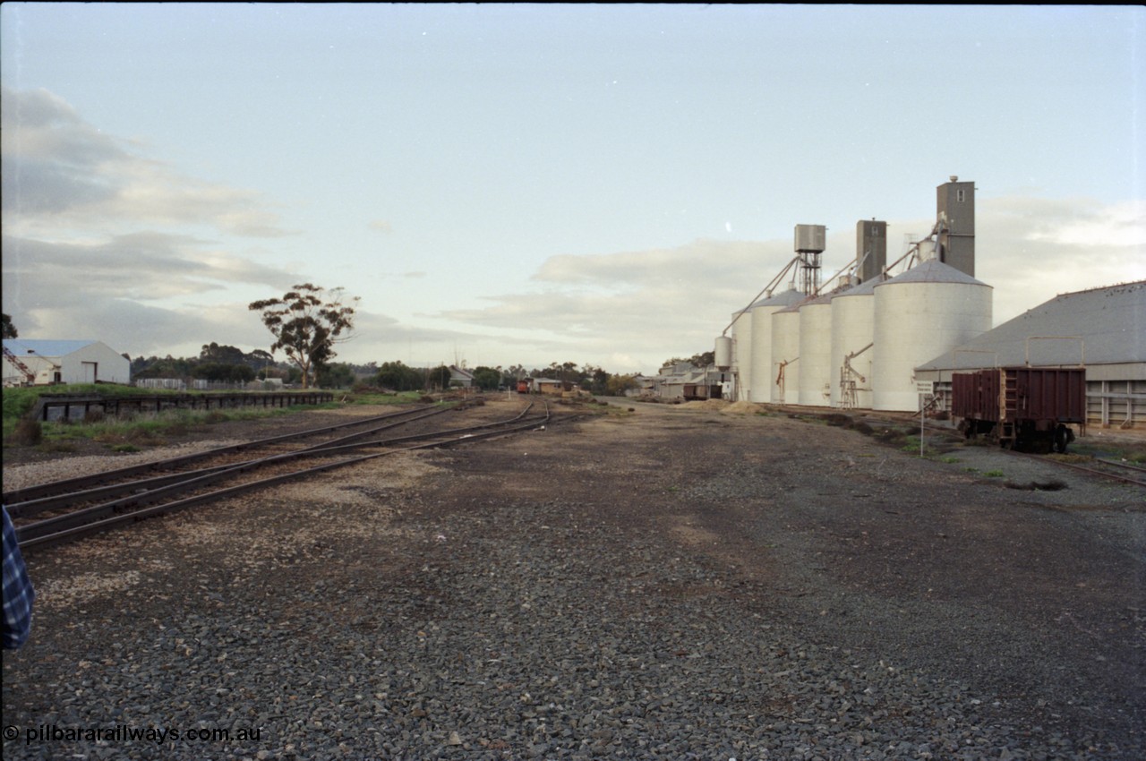 136-24
Deniliquin station yard overview looking north from Wood St, loading ramp and platform, RT can be seen in the background at the station building, grain sheds, Ascom silo complex, Victorian Oats Pool shed and VZTX class sleeper carrying waggon.
