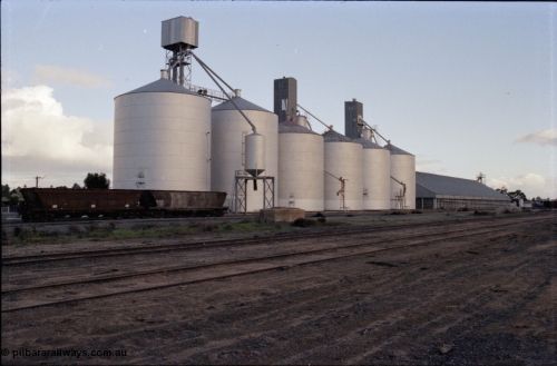 136-11
Deniliquin silo complex overview with Ascom style silos and a horizontal Victorian Oats Pool shed, yard view, broad gauge V/Line VHGF and VHGY class bogie grain waggons still in VR arrow livery.
Keywords: VHGF-type;VHGY-type;