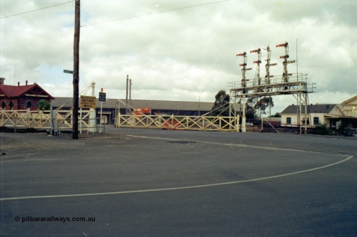 139-14
Ballarat, view of Lydiard Street interlocked crossing gates and semaphore signal bridge, signal box is just to the left of frame, and station is to the right. Ballarat Coachlines on the brick building on the left, entrance to Ballarat Freightgate in middle of frame at V/Line sign.
