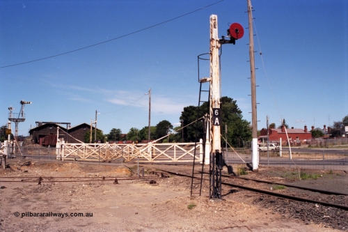 140-1-05
Ballarat East yard view, disc signal post 6A stands sentinel to the entry to Ballarat East Loco Depot with the second set of interlocked gates for the crossing of Humffray St, goods sheds in the background.
