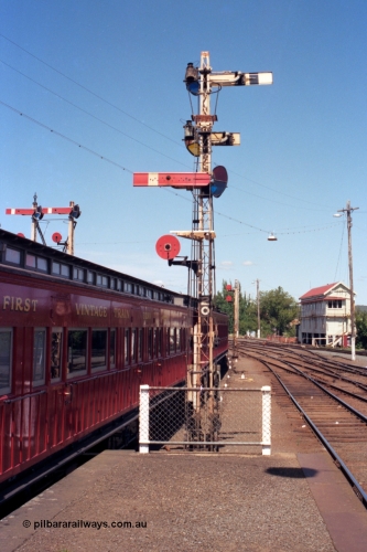 140-1-12
Ballarat station platform 2 looking towards Ballarat signal box A, semaphore signal post 20, the facing semaphore is the up home signal to the up passenger line and the disc is for the goods departure or Siding Y, the two semaphores facing away are the down home for No.4 Rd (platform road) and the calling on for No.4 Rd, double disc signal post 17 in the distance, quad disc signal post 16 on the right and the top of semaphore signal post 19 is visible over the passenger carriage.
