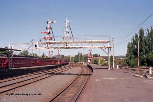 140-1-13
Ballarat station platform view from platform 1, E cars on No.5 Rd, looking east, A Box in the background, signal gantry semaphore signal post 23 is still in use, but as No.2 Rd has been removed signal post 22 has been stripped.
