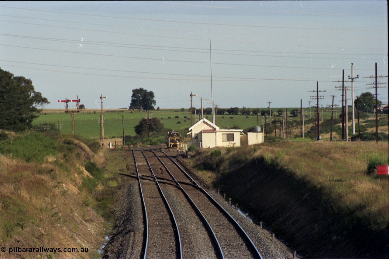 140-2-08
Warrenheip, station overview looking south, semaphore signal post 11 with co-acting up home semaphore arms, the signal pulled off is the down starting semaphore, the line to Melbourne (direct) curves to the left and the Geelong line around to the right.
