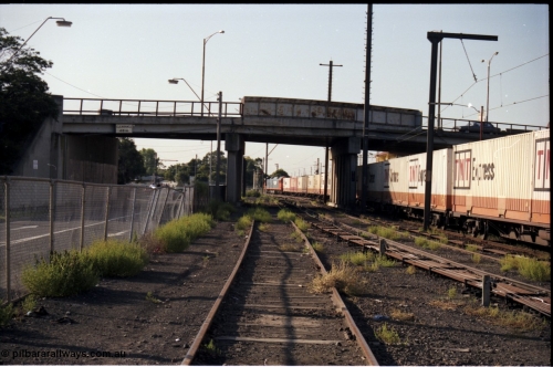 141-2-16
Sunshine view looking north with Adelaide bound goods train running past platform three and under the Hampshire Road overbridge, the track I'm standing on is the old No.5 road, No.4 is the other side of the point rodding, while the train is on No.3 road, the goods shed was behind me, point rodding and signal wires.
