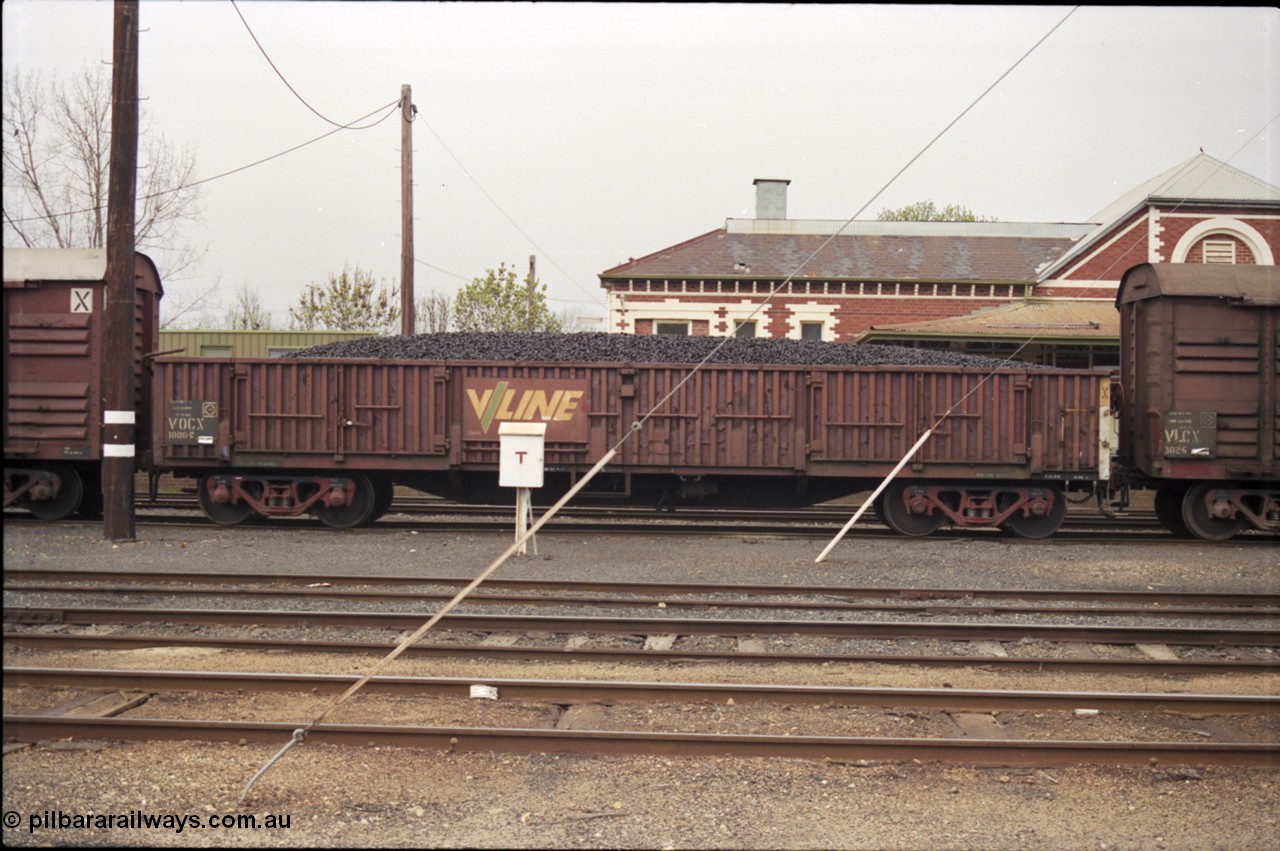 142-1-31
Benalla yard, V/Line stabled broad gauge train 9303 Wodonga goods, VOCX type bogie open waggon VOCX 1006 loaded with briquettes, started life built at Victorian Railways Bendigo Workshops in October 1974 as ELX type ELX 1006, reclassified to VOCX type in August 1979, telephone box in front, station building behind, side view.
Keywords: VOCX-type;VOCX1006;Victorian-Railways-Bendigo-WS;ELX-type;