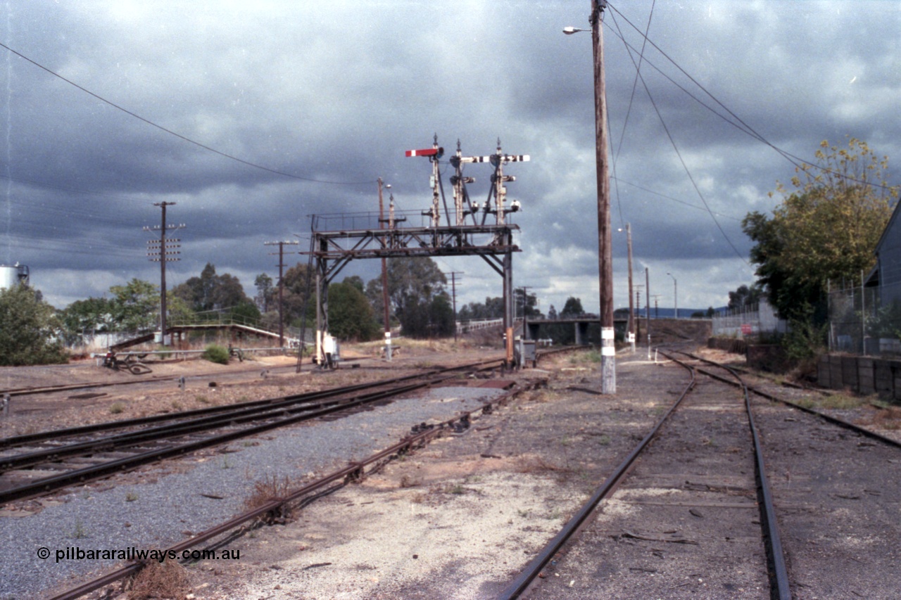 148-26
Wangaratta, Signal Bridge at Down end of yard, looking south, Up Signal Post 9 was one arm and two discs, the Arm Home Signal from 'A' to No. 1 Road to Post 20, the removed discs were from 'A' to Siding 'F' and from 'A' to Cattle Sidings. Down semaphore and disc Signal Posts 7, 8 and 10 facing away, rodding for mainline points visible, fuel siding at left with footbridge over standard gauge line, Roy Street overbridge in the distance, Sidings E and Works platform at right.
