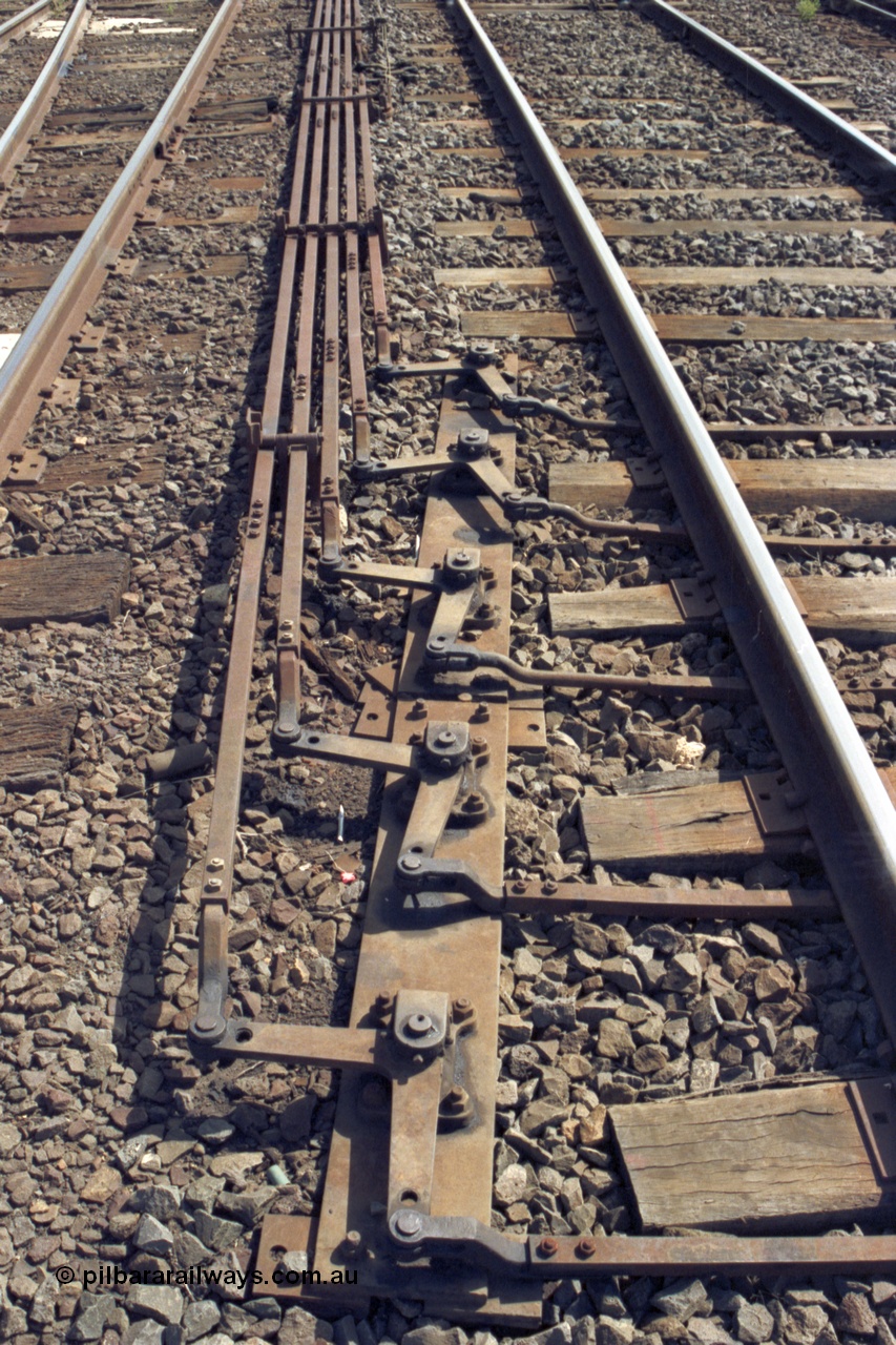 149-14
Bacchus Marsh, track view of point rodding changing track sides under rails with pivots.
