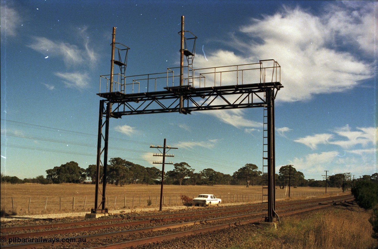 153-2-02
Bank Box Loop, broad gauge track view of redundant signal gantry following loop extension back in 1982, looking towards Ballarat, HK Holden framed under gantry.
