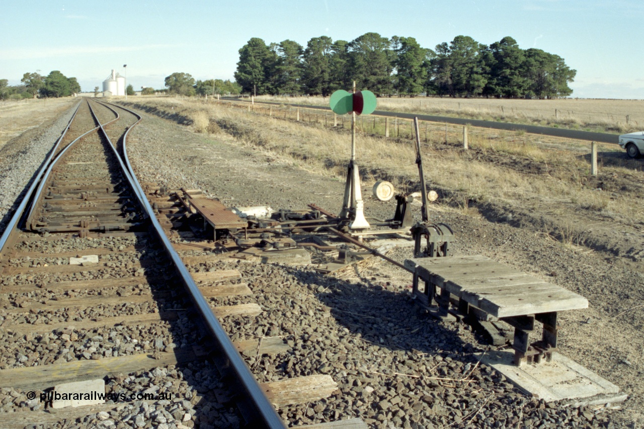 153-3-06
Tatyoon station yard overview from Ararat end, shows trailable points lever and indicator, goods shed and Murphy silos visible in the background.
