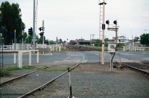 156-11
Shepparton station yard view looking north across High Street grade crossing, dwarf signal 8 just across road, SPC Siding and building in the background, searchlight signals in the distance are up and down home signals at Fryers Road grade crossing, down home signal post 10 and up home signal post 12, point lever, electric interlocking and phone cabinet.
