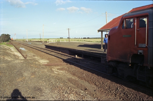 157-01
Gheringhap, station view looking east from former up platform, V/Line broad gauge A class A 77 Clyde Engineering EMD model AAT22C-2R serial 83-1181 rebuilt from B 77 Clyde Engineering EMD model ML2 serial ML2-18 leads the up Ararat to Melbourne via Nth Geelong passenger train, as the signaller prepares to swap electric staves with the crew, a down grain train 9121 sits in Siding A, station platform, point rodding and semaphore signals.
Keywords: A-class;A77;Clyde-Engineering-Rosewater-SA;EMD;AAT22C-2R;83-1181;rebuild;bulldog;
