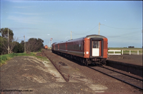 157-02
Gheringhap, station view looking east from former up platform, V/Line broad gauge A class A 77 Clyde Engineering EMD model AAT22C-2R serial 83-1181 rebuilt from B 77 Clyde Engineering EMD model ML2 serial ML2-18 leads the up Ararat to Melbourne via Nth Geelong passenger train with a three car N set, along the mainline heading now for North Geelong, a down grain train 9121 sits in Siding A, station platform, point rodding and semaphore signals.
