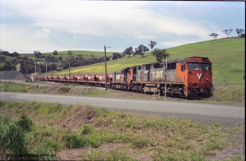157-31
Kilmore East, Apex Quarry Siding, V/Line broad gauge locomotives N class N 471 'City of Benalla' Clyde Engineering EMD model JT22HC-2 serial 87-1200 and T class T 390 Clyde Engineering EMD model G8B serial 65-420 with train under the loading bins during loading operations, view across Broadford - Kilmore Road.
Keywords: N-class;N471;Clyde-Engineering-Somerton-Victoria;EMD;JT22HC-2;87-1200;