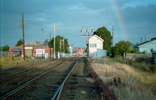 159-19
Ballarat D Signal Box, Linton Junction, broad gauge track view from the points for the Cattle Yard Line looking east, Linton Line then the Ararat Line with the down crossover visible, triple doll semaphore signal 20 facing down trains behind the signal box, with the Gillies Street interlocked gates, staff exchange platform and up home semaphore signal post 19, a V/Line G class awaits line clear to Trawalla with a down goods train stopped just east of Gillies Street gates, points, interlocking, track work and point rodding.
