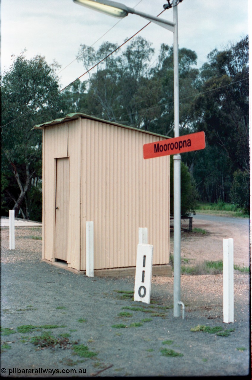 160-16
Mooroopna, 110 Mile Post and station name sign planted in the platform, the building behind it is a lamp room or WC?
