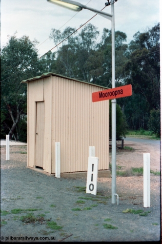 160-16
Mooroopna, 110 Mile Post and station name sign planted in the platform, the building behind it is a lamp room or WC?
