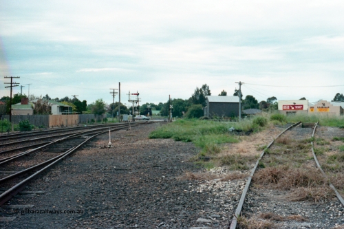 161-06
Numurkah, yard view looking north towards Strathmerton, semaphore signal post 4 still has the Strathmerton line semaphore but the Picola line semaphore has been removed, Picola Junction is just over the grade crossing around the curve, track at right is heading across the ash pit to the turntable, the grass in the middle between the yard and turntable road used to have two sidings in there.
