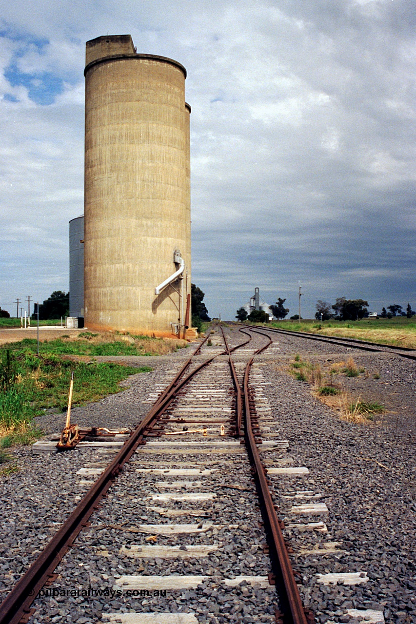 170-05
Dookie, yard overview looking west, crossover with hand locking bar to mainline on the right, gravitational road runs along the front of the Williamstown style silo complex with steel annex visible, GEB sub-terminal in the background.
