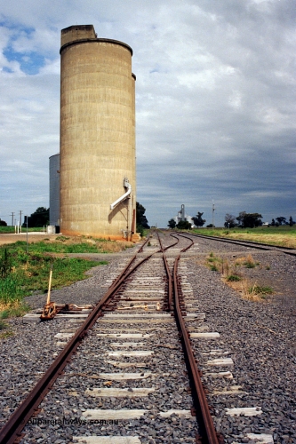 170-05
Dookie, yard overview looking west, crossover with hand locking bar to mainline on the right, gravitational road runs along the front of the Williamstown style silo complex with steel annex visible, GEB sub-terminal in the background.
