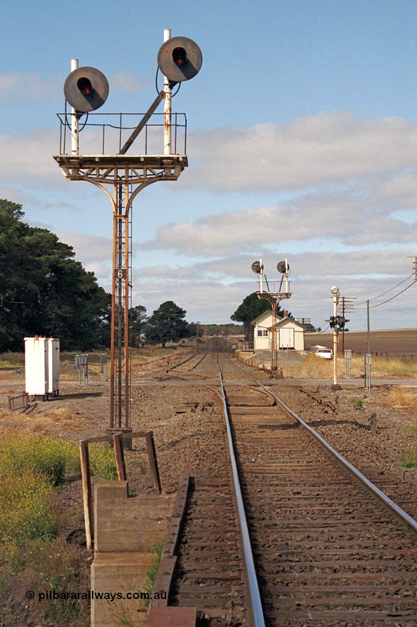 171-09
Trawalla station yard overview, looking towards Melbourne down main line, Up Home searchlight signal Post 6, left hand post Home from Main Line to No. 2A via No. 2 Road to Post 3 and the right hand post Home from Main Line to No. 1 Road to Post 3. Waterloo Road grade crossing, points and rodding, searchlight signal Post 5 facing away, station building and signal box in the distance.
