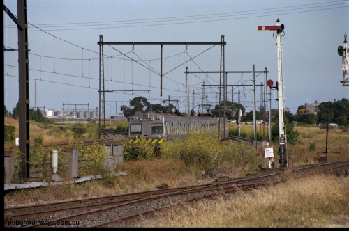 172-01
Sunshine, broad gauge Melbourne metropolitan electric service operated by 'The Met', this up Hitachi 6 car 'spark' or electric train rounds the curve east of Sunshine as it heads to Tottenham, signal post 49 controls up trains on the Sunshine - Newport Loop Line, with the disc controlling access to the GEB sidings, the points facing the camera leads to the main running lines and the Sunshine yard or what remained of it.

