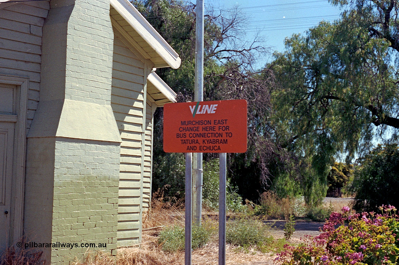 173-14
Murchison East, V/Line station sign, 'Change here for bus connection to...', north end of station building with brick chimney.
