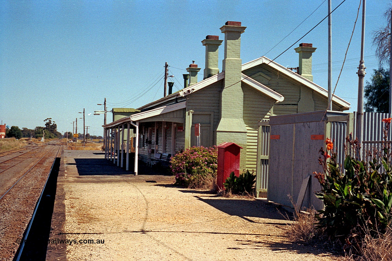 173-15
Murchison East, station building and platform overview looking south towards Melbourne, ablution block, fire hose cabinet, station building with a number of brick chimneys.
