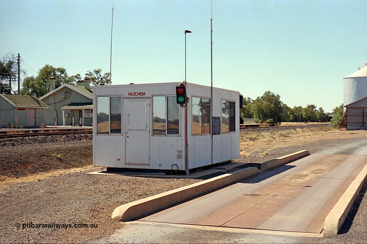 173-18
Murchison East, modern road vehicle weighbridge with portable cabin and traffic lights for weighing of in-bound grain receivals, station building and goods shed behind.
