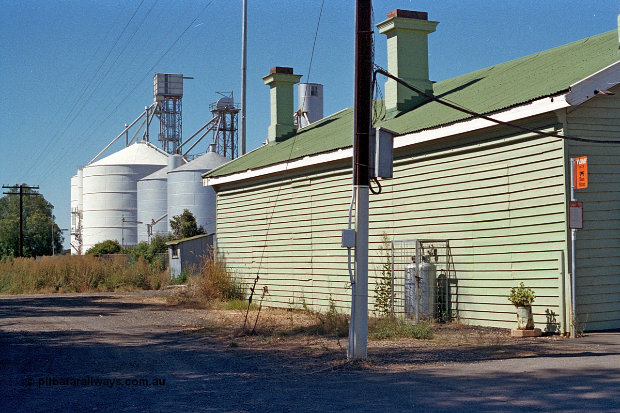 173-23
Murchison East, rear view of station building looking north, shows bus stop sign, gas cylinders and both Ascom and Ascom Jumbo style silos complexes.
