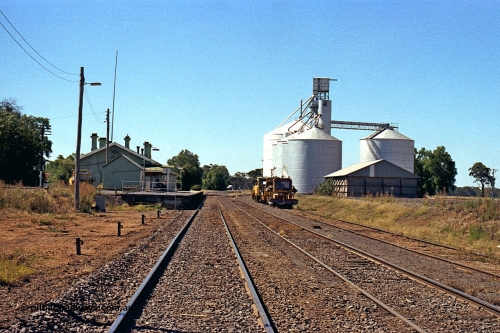 173-21
Murchison East, station yard overview looking north, goods shed and station building and platform, track machines, and horizontal grain bin with Murphy, with steel annex, and Ascom Jumbo style silo complexes.
