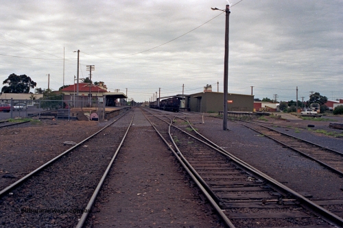175-05
Shepparton station yard overview looking south, between No.1 and No.2 roads, points to No.3 and 4 roads, stabled fuel train in front of new style goods shed, loading platform, station building and platform on the left.
