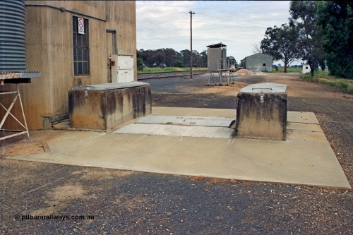 175-23
Pine Lodge, view of road receival point, or truck unloading dump point for a Williamstown style silo complex, GEB sampling gantry, with super phosphate shed in the background, road vehicle weighbridge visible on the right.
