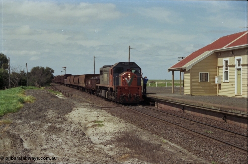 179-03
Gheringhap, station building and platform view with down broad gauge goods train 9153 behind V/Line X class loco X 53 with serial 75-800 a Clyde Engineering Rosewater SA built EMD model G26C, as the signaller swaps the electric staff from North Geelong C Box for a train order to Maroona.
Keywords: X-class;X53;Clyde-Engineering-Rosewater-SA;EMD;G26C;75-800;