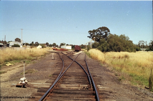 182-04
Wahgunyah, station yard overview looking north along No.1 Road, rake of bogie waggons on No.2 Road with Delarue silo complex on site of former station building, points with hand locking bar, road curving around to the left is for the super phosphate sheds, portable station building and red gum sleeper stockpile in middle frame.
