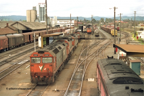 184-08
Albury station yard and loco depot fuel point overview looking north, V/Line standard gauge locos lined up awaiting the Sunday run of goods trains back to Melbourne, G class G 527 Clyde Engineering EMD model JT26C-2SS serial 88-1257, C class C 503 Clyde Engineering EMD model GT26C serial 76-826 and G class units G 520 serial 85-1233, G 525 serial 86-1238 and G 523 serial 86-1236, goods shed at left behind louvre vans, the stabled train beside the locos is SM5, elevated view.
Keywords: G-class;G527;Clyde-Engineering-Somerton-Victoria;EMD;JT26C-2SS;88-1257;C-class;C503;GT26C;76-826;G520;85-1233;G525;86-1238;G523;86-1236;