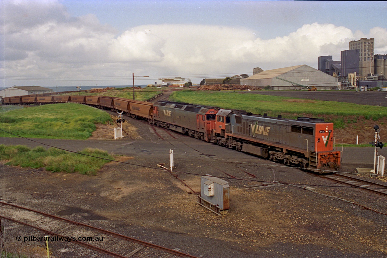 185-12
North Geelong Grain Loop view from Corio Quay Road across Access Road grade crossing with the tracks to Corio Quay at the very bottom of image, as the grain train behind V/Line locos X class locomotive X 41 Clyde Engineering EMD model G26C serial 70-704 long end leading and G class locomotive G 528 Clyde Engineering EMD model JT26C-2SS serial 88-1258 having past the Home Signal and crossing the former tracks for the Freezing Works Sidings.
Keywords: X-class;X41;Clyde-Engineering-Granville-NSW;EMD;G26C;70-704;