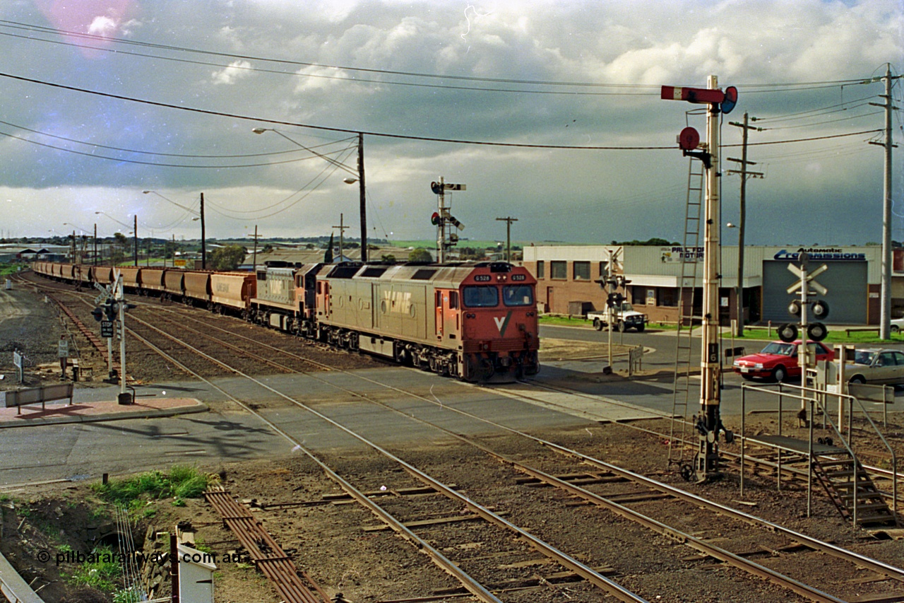 185-18
North Geelong C Box, view from signal box balcony of Separation Street grade crossing as V/Line grain loop shunt engines G class G 528 Clyde Engineering EMD model JT26C-2SS serial 88-1258 and X class X 41 Clyde Engineering EMD model G26C serial 70-704 lead the final days loaded grain consists past semaphore signal post 14 bound for the grain loop, semaphore signal post 16 and the staff exchange platform are also visible.
Keywords: G-class;G528;Clyde-Engineering-Somerton-Victoria;EMD;JT26C-2SS;88-1258;