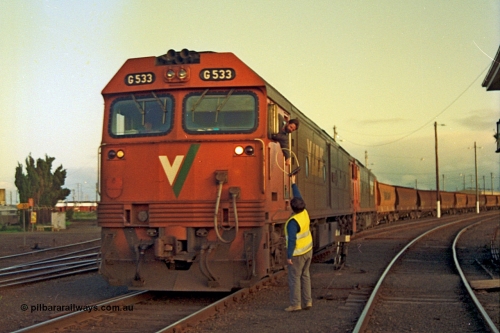 185-34
North Geelong C Box, V/Line down grain train number 9125 departs the yard as the driver leans out the window and collects the electric staff off the signaller for the section to Gheringhap from the cab of G class G 533 Clyde Engineering EMD model JT26C-2SS serial 88-1263, with a sister unit trailing, ground dwarf disc signal post 18 is pulled off for the move.
Keywords: G-class;G533;Clyde-Engineering-Somerton-Victoria;EMD;JT26C-2SS;88-1263;