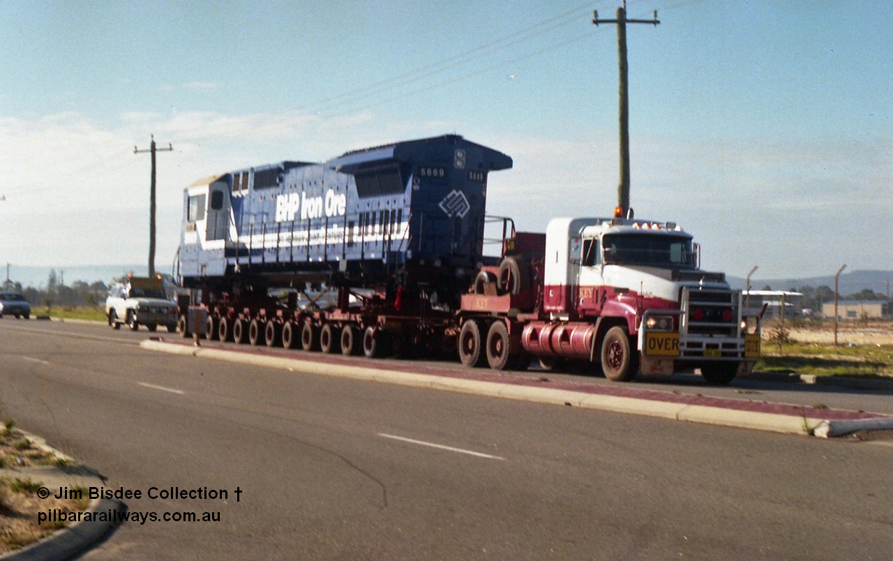 24134
Bassendean, Collier Road, Key Transport hauling the final BHP Iron Ore Goninan GE rebuilt CM40-8M unit 5669 serial 8412-02 / 95-160, which is actually an CM40-8MEFI as the final three had electronic fuel injection fitted to their 7FDL-16 engines. 5669 was rebuilt from Comeng NSW built ALCo M636 model 5486 serial C6084-2. July 1995.
Jim Bisdee photo.
Keywords: 5669;Goninan;GE;CM40-8EFI;8412-02/95-160;rebuild;Comeng-NSW;ALCo;M636C;5486;C6084-2;