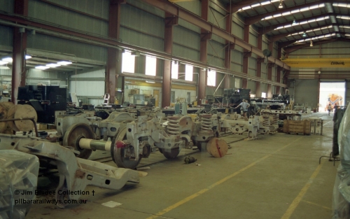 22668
Bassendean, during an Open Day at the Goninan workshops, a stripped back ALCo locomotive frame under re-construction which will become a GE CM40-8M in the background and some ALCo Hi-Ad trucks being overhauled. 20th July 1991.
Jim Bisdee photo.
